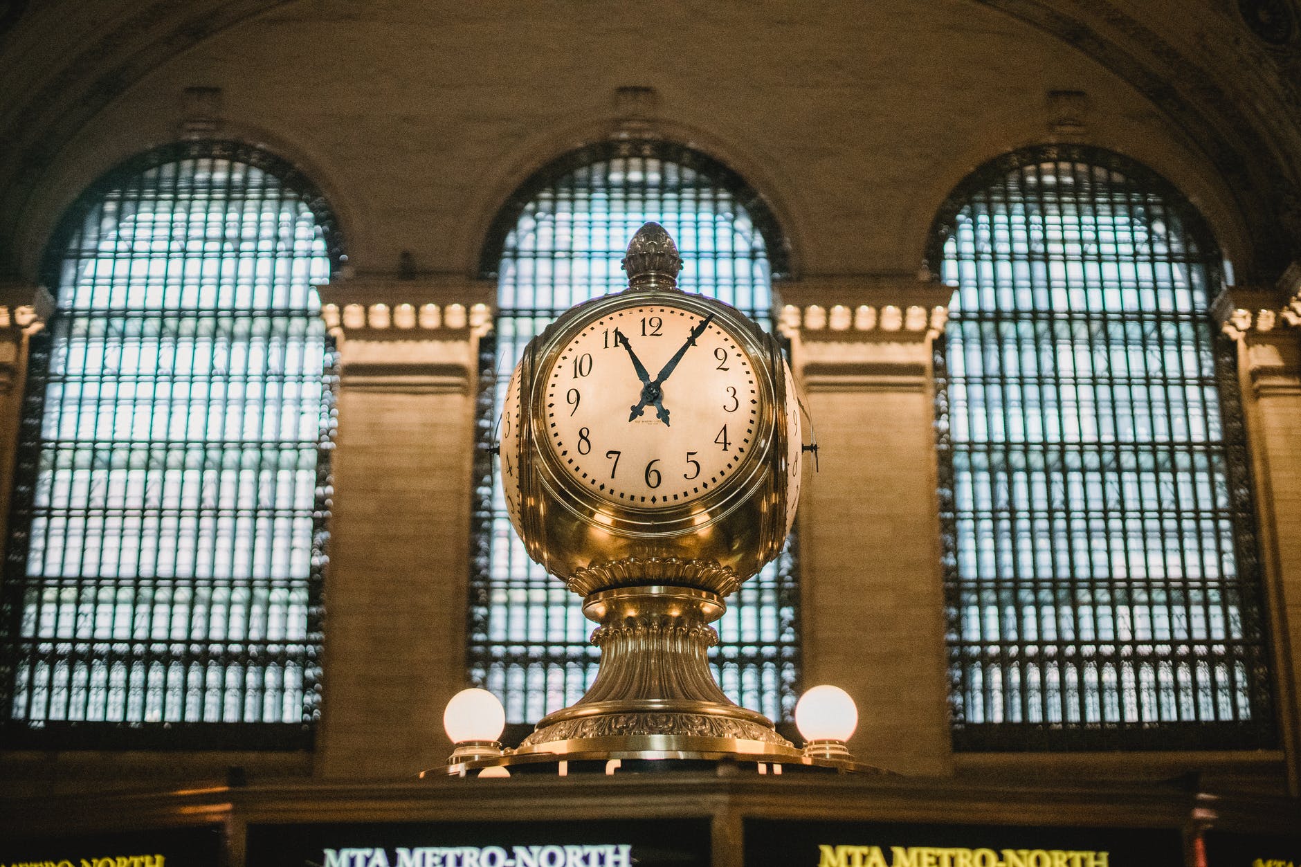 vintage golden clock in aged railway station terminal with arched windows